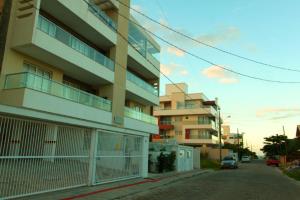 an apartment building with a fence in front of a street at Edificio Villa Milano in Bombinhas