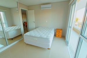 a bedroom with a mirror and a bed in it at Edificio Villa Milano in Bombinhas