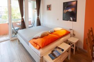 Bett mit orangefarbenen Kissen in einem Zimmer mit Fenster in der Unterkunft Chic Cosy Quiet in Ljubljana Center in Ljubljana
