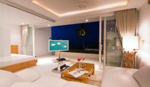 a living room with a white couch and a tv at Code Samui Hotel in Mae Nam