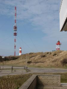 un faro rojo y blanco en la cima de una colina en Strandhotel-Najade, en Borkum