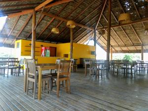 a restaurant with wooden tables and chairs and a yellow wall at Ap 2/4 na Reserva Imbassaí in Imbassai