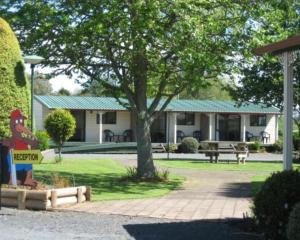 a house with a chicken sign in front of it at Otorohanga Kiwi Holiday Park in Otorohanga