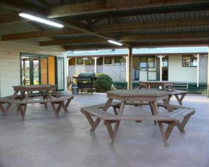 3 mesas de picnic en un patio con parrilla en Otorohanga Kiwi Holiday Park en Otorohanga