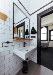 a white bathroom with a sink and a mirror at East Brunswick Hotel in Melbourne