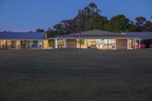 a building with a large field in front of it at Club Inn Motel in West Wyalong