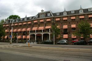 een groot bakstenen gebouw met rode luifels op een straat bij The Manor Amsterdam in Amsterdam