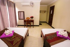 two beds in a hotel room with a table at Blue Diamond Hostel in Battambang