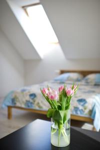 wazon z różowymi kwiatami na stole w obiekcie Karklės Villa w mieście Karklė