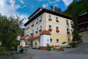 un gran edificio blanco con flores en las ventanas en Hotel Kirchenwirt, en Bad Kleinkirchheim