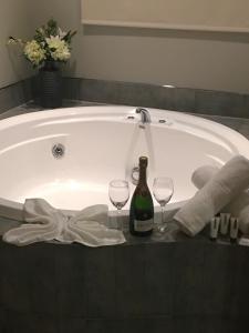 a bath tub with a bottle of wine and two wine glasses at Village Motel in Havelock North