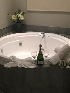 a bath tub with a bottle of wine and two wine glasses at Village Motel in Havelock North