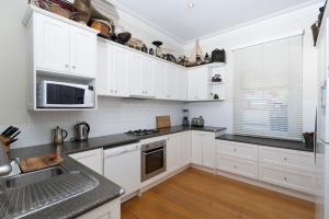 una cocina con armarios blancos y encimeras negras en Abaleen House en Queenscliff
