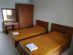 Duas camas individuais num quarto com um espelho. em Thana Place Charunsanitwong 34 em Bangkok