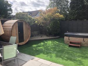 a small backyard with a wooden sauna and green grass at Bournemouth Hot Tub & Sauna Holiday Let in Bournemouth