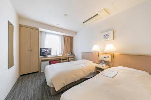a hotel room with two beds and a desk at Ginza Capital Hotel Akane in Tokyo