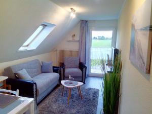 a living room with a couch and a table and a window at Ferienwohnung Deichstr De Lorenzo in Carolinensiel