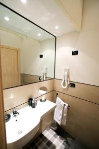 La salle de bains est pourvue d'un lavabo et d'un grand miroir. dans l'établissement Residence Arco Antico, à Syracuse
