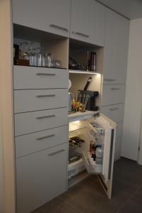 La cuisine est équipée de placards blancs et d'un réfrigérateur ouvert. dans l'établissement BnB Sirnach, à Sirnach