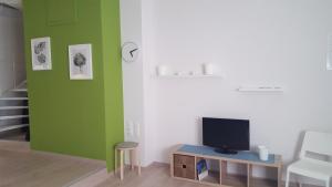 a living room with green and white walls and a tv at Erato Apartment in Heraklio