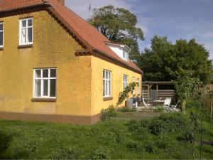 een geel huis met twee ramen en een tuin bij A Big Holidayhouse Rømø-Rim-Ribe in Skærbæk
