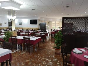 a dining room with tables and chairs and a television at Hotel Santa Ana in La Carlota