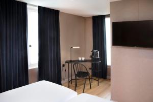 una camera d'albergo con letto, tavolo e TV di Hôtel du Jardin des Plantes a Parigi