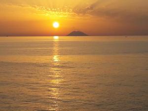 a sunset over the ocean with a mountain in the background at Residenza Villa Spagnola in Parghelia