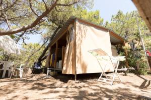 a tiny house with a tent and a chair at Camping Continental in Marina di Castagneto Carducci