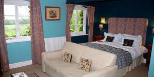 a bedroom with a bed and a couch and windows at Lower Buckton Country House in Leintwardine