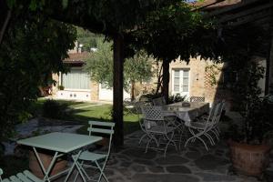 a patio with a table and chairs under an umbrella at Dimora delle Camelie in SantʼAndrea di Compito