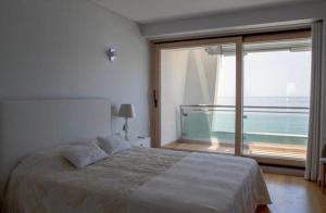 a bedroom with a bed and a large window at Praia da California Apartment in Sesimbra