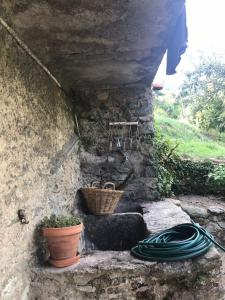 a stone wall with a basket and a hose at Gîte Aghja suttana l'incantu in Santa-Lucia-di-Mercurio