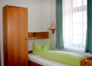 a bedroom with a bed with green pillows and a window at Landhotel und Gasthof Stadt Nürnberg in Ahlsdorf