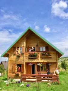 une maison en rondins avec des personnes assises sur le balcon dans l'établissement Sunnyside, à Žabljak