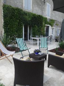 a patio with two lawn chairs and a table and chairs at Les Tilleuls - Chambres d'hôtes - La Rochefoucauld in La Rochefoucauld