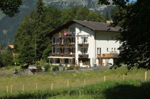 un grand bâtiment blanc sur une colline dans un champ dans l'établissement Hotel Berghaus, à Wengen