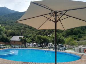 Camping Prado Verde في Vilamós: جلسه مظله بيضاء بجانب مسبح