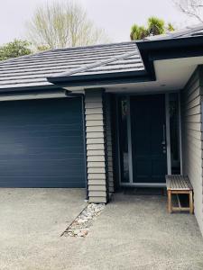 uma garagem com uma porta azul e um banco em Memorial holiday home em Christchurch