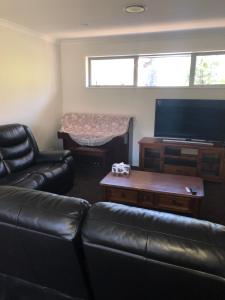 uma sala de estar com um sofá de couro e uma televisão de ecrã plano em Memorial holiday home em Christchurch