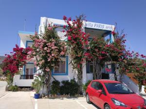 a red car parked in front of a building with flowers at Villa Paris in Xerokampos