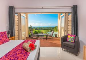 a bedroom with a bed and a balcony with a view at Rarotonga GolfSeaView in Rarotonga
