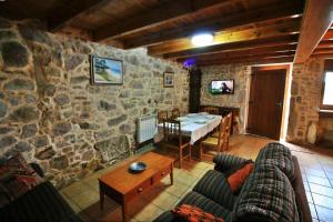 sala de estar con mesa y pared de piedra en Casa Porto de Quilmas, en O Pindo