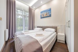 um quarto com uma cama grande e lençóis brancos em Apartamenty Cypel Helski em Hel