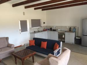 a living room with a blue couch and a kitchen at Pepper Tree Cottage in De Rust