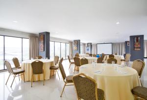 a dining room with tables and chairs and windows at Ibis Budget Jakarta Daan Mogot in Jakarta