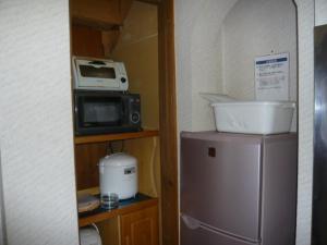 a small kitchen with a microwave and a refrigerator at Hakuba Happo Log Chalets in Hakuba