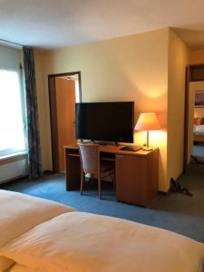 a hotel room with a bed and a desk with a television at Hotel Eintracht in Oberbipp