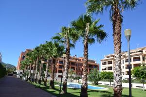 una fila de palmeras frente a un edificio en Jardines de Las Marinas - Royal Suite, en Denia