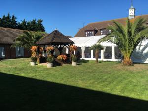 a house with a gazebo and palm trees in a yard at The Abbey Hotel and conference centre in Minster